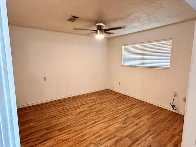 empty room with a textured ceiling, ceiling fan, and hardwood / wood-style flooring