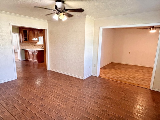 empty room with dark hardwood / wood-style floors, crown molding, and a textured ceiling