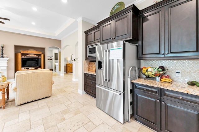 kitchen with tasteful backsplash, ceiling fan, appliances with stainless steel finishes, dark brown cabinets, and light stone counters