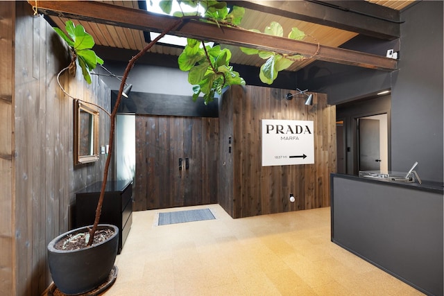 interior space featuring beam ceiling and wood walls