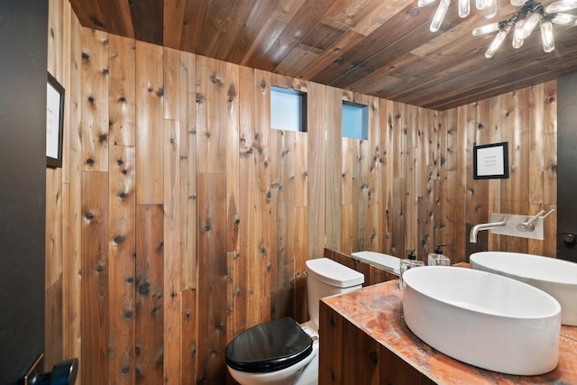 bathroom with toilet, vanity, wood walls, and wood ceiling