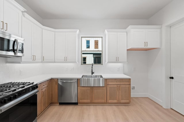 kitchen with white cabinetry, sink, backsplash, light hardwood / wood-style floors, and stainless steel appliances