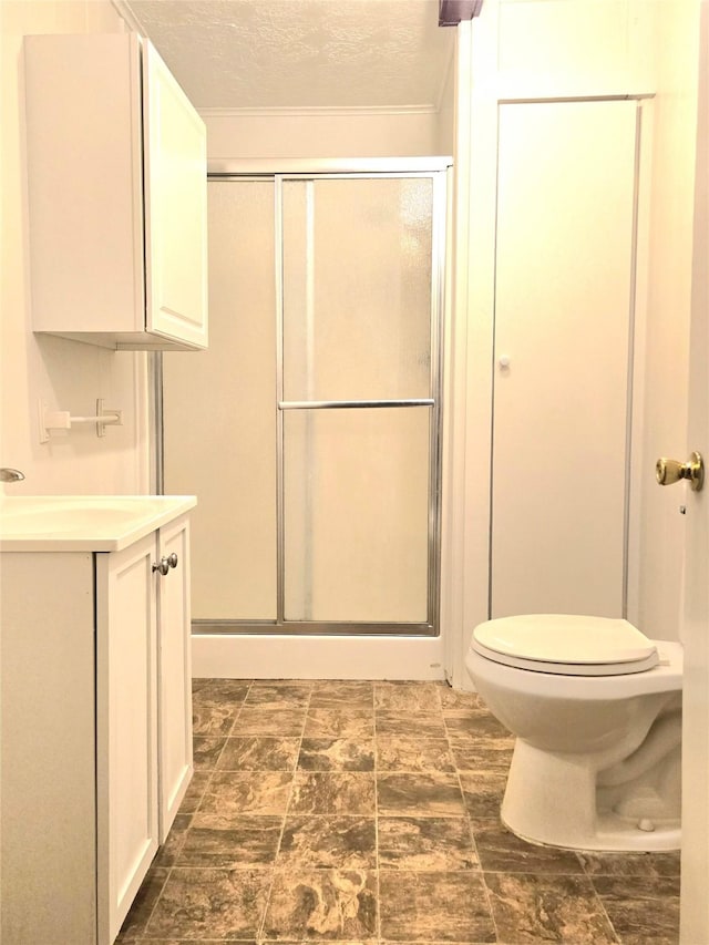 bathroom featuring a textured ceiling, toilet, walk in shower, and vanity