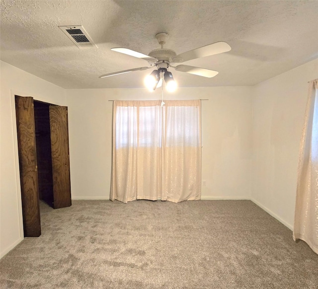 unfurnished room with carpet, ceiling fan, and a textured ceiling