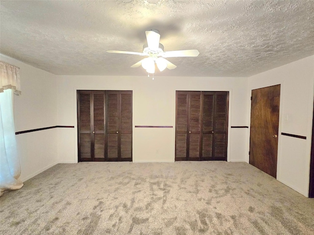 unfurnished bedroom featuring ceiling fan, carpet, and multiple closets