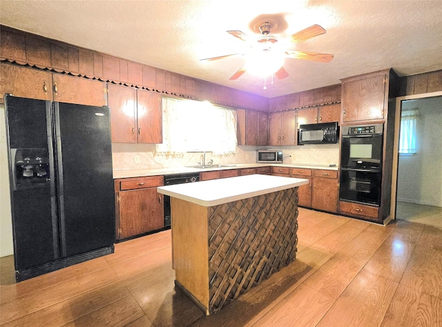 kitchen featuring ceiling fan, light hardwood / wood-style floors, black appliances, sink, and a textured ceiling