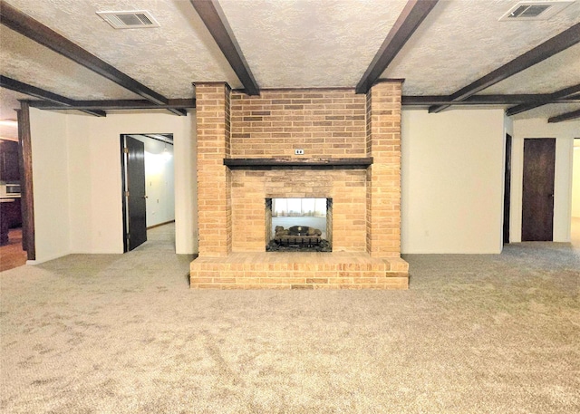 unfurnished living room with a textured ceiling, a brick fireplace, carpet, and beamed ceiling