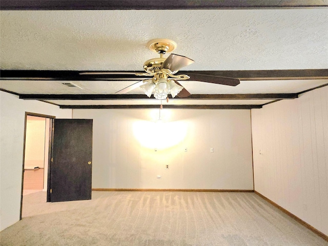 unfurnished room with a textured ceiling, ceiling fan, light colored carpet, and beamed ceiling