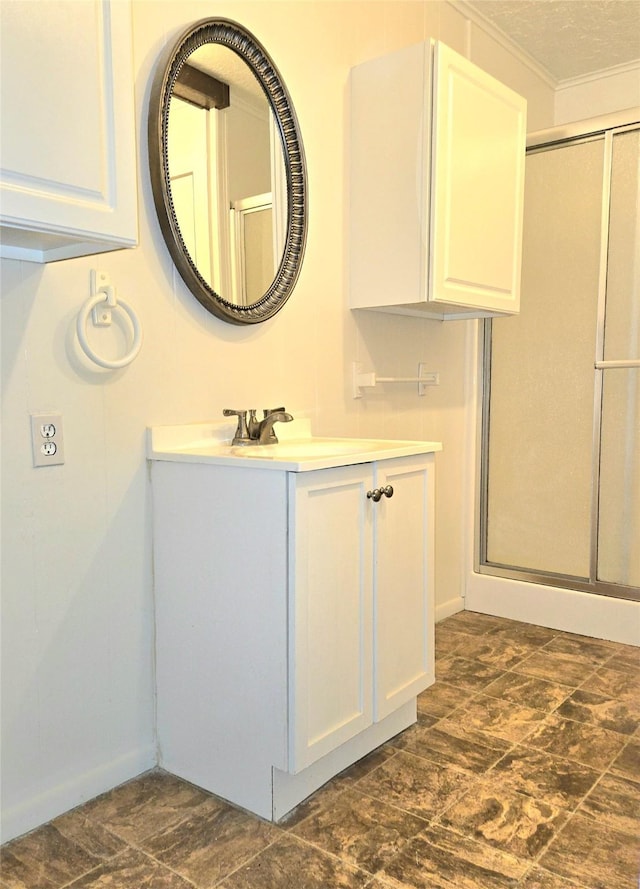 bathroom featuring a textured ceiling, ornamental molding, a shower with shower door, and vanity