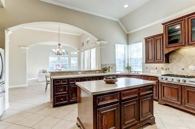 kitchen with a center island, a notable chandelier, stainless steel gas cooktop, hanging light fixtures, and sink