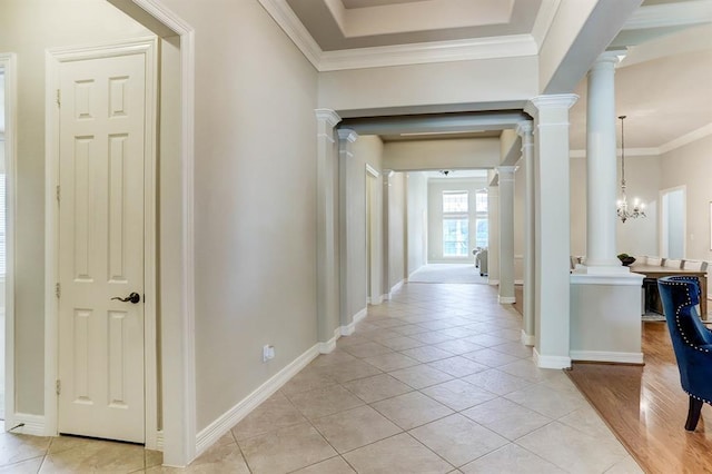 hall with light tile patterned floors, ornamental molding, and a notable chandelier