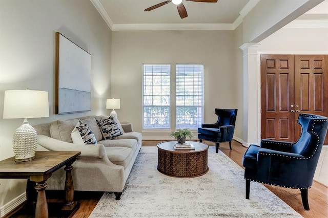 living room featuring ceiling fan, crown molding, wood-type flooring, and ornate columns