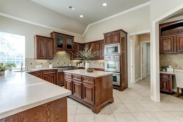 kitchen with appliances with stainless steel finishes, a center island, lofted ceiling, sink, and light tile patterned floors