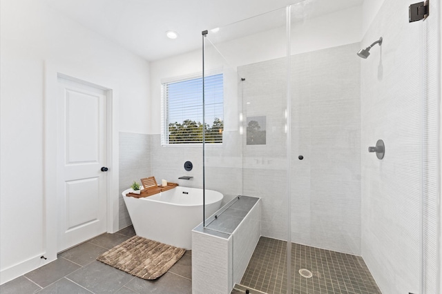 bathroom with tile walls, tile patterned floors, and shower with separate bathtub