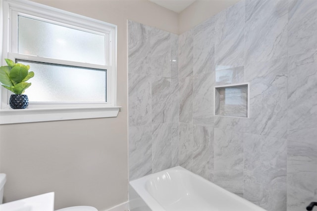 bathroom with toilet and tiled shower / bath