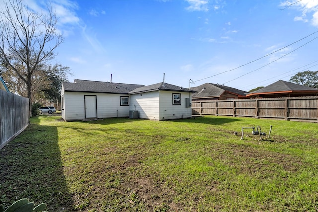 rear view of property with cooling unit and a yard