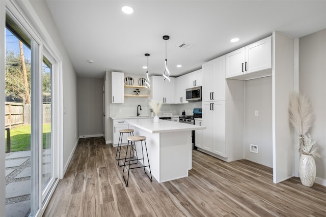 kitchen with white cabinetry, stainless steel appliances, a center island, decorative light fixtures, and sink