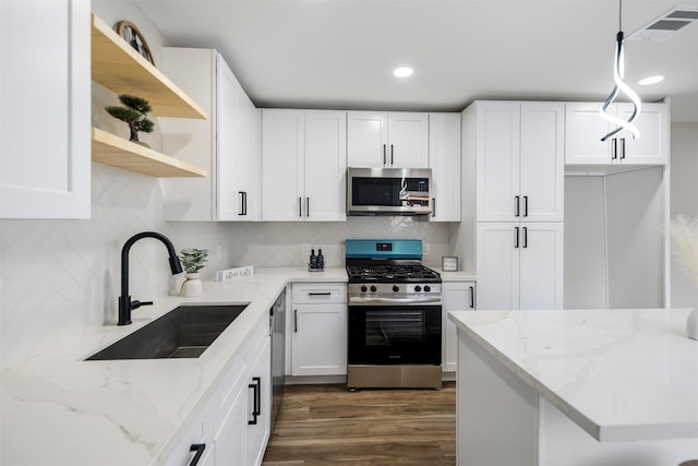 kitchen with decorative light fixtures, white cabinetry, stainless steel appliances, sink, and light stone counters