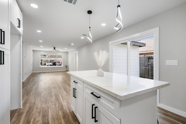 kitchen featuring ceiling fan, white cabinetry, a center island, and decorative light fixtures