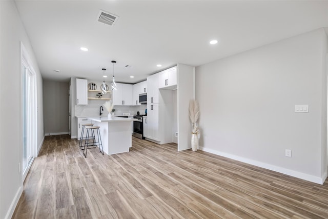 kitchen featuring appliances with stainless steel finishes, a kitchen island, pendant lighting, white cabinets, and a breakfast bar