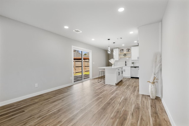 kitchen featuring a kitchen island, stainless steel dishwasher, a kitchen bar, hanging light fixtures, and white cabinets