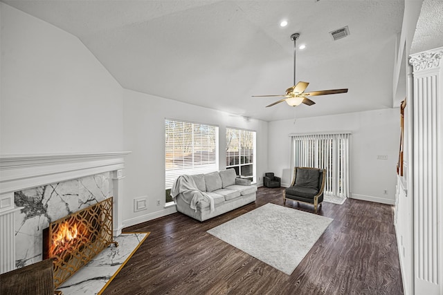 living room with a fireplace, a textured ceiling, ceiling fan, dark hardwood / wood-style floors, and lofted ceiling