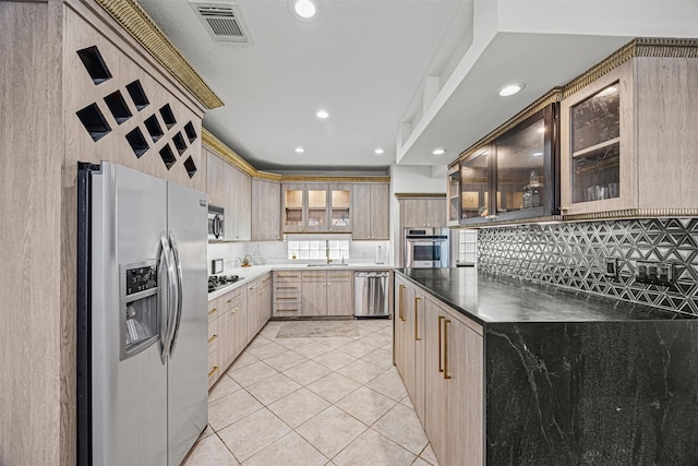 kitchen with appliances with stainless steel finishes, light brown cabinets, tasteful backsplash, sink, and light tile patterned floors