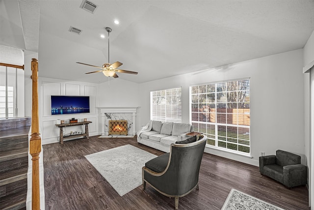 living room with a wealth of natural light, dark hardwood / wood-style flooring, lofted ceiling, and a premium fireplace