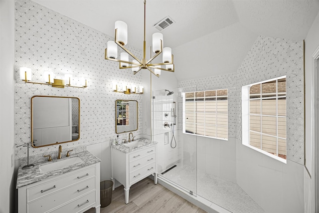 bathroom featuring vanity, hardwood / wood-style floors, a tile shower, and lofted ceiling