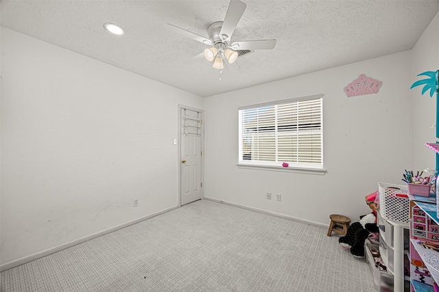 interior space with ceiling fan, light colored carpet, and a textured ceiling