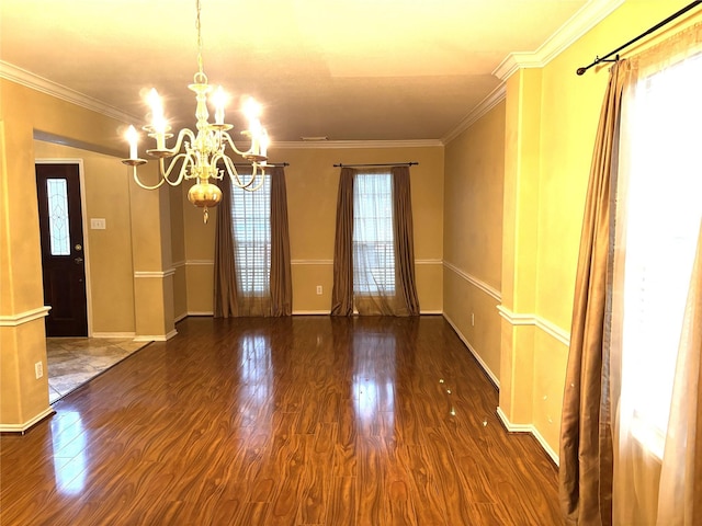 spare room with crown molding, dark wood-type flooring, and a notable chandelier