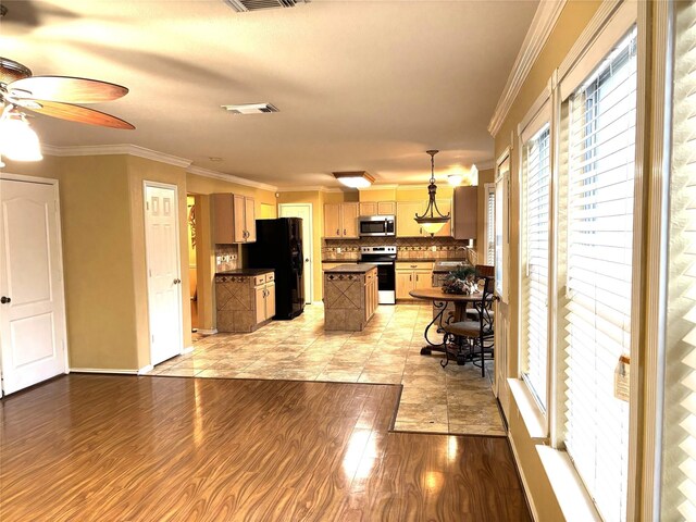 kitchen featuring pendant lighting, light hardwood / wood-style flooring, appliances with stainless steel finishes, ornamental molding, and decorative backsplash