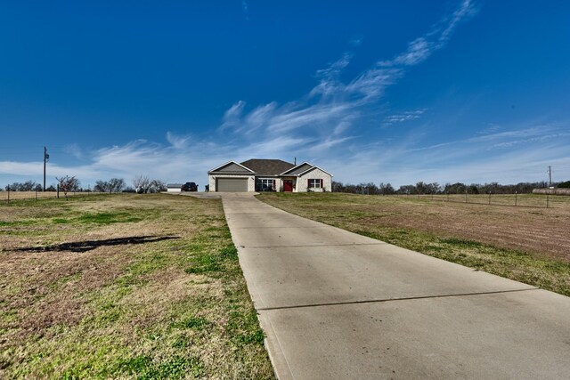 ranch-style home with a garage, a front yard, and a rural view