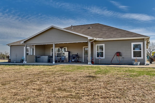 rear view of property featuring a patio area, a yard, and a jacuzzi