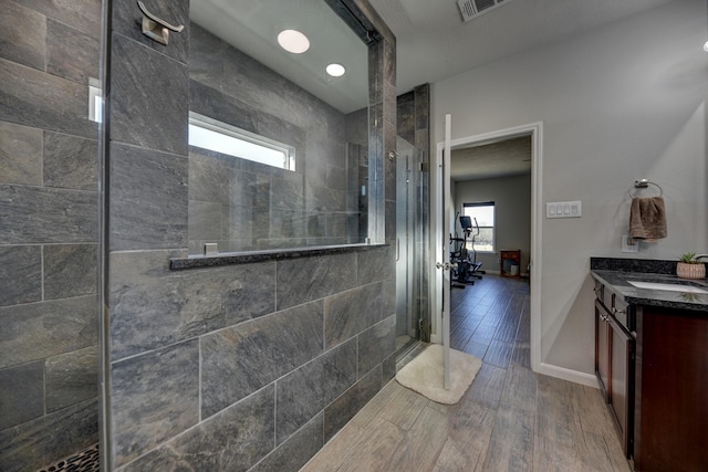 bathroom with hardwood / wood-style floors, tiled shower, and vanity