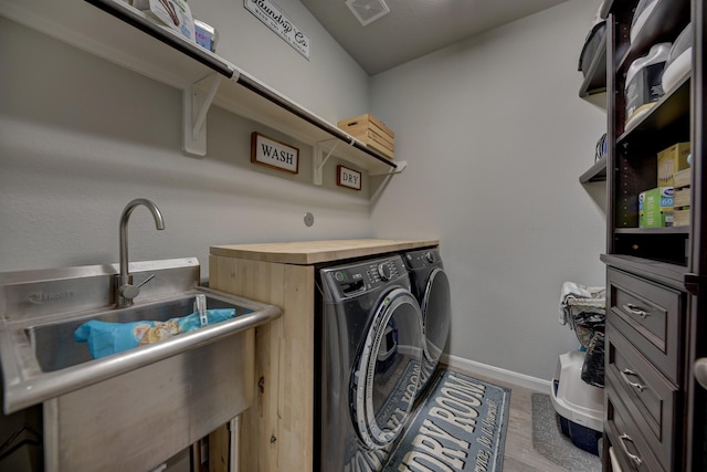 clothes washing area with sink, light hardwood / wood-style flooring, and washer and dryer