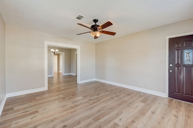 empty room featuring light wood-type flooring and ceiling fan with notable chandelier