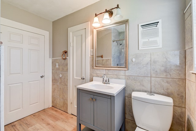 bathroom with toilet, tile walls, hardwood / wood-style flooring, and vanity