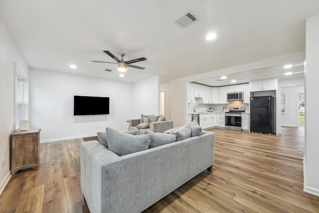 living room featuring ceiling fan, hardwood / wood-style floors, and sink