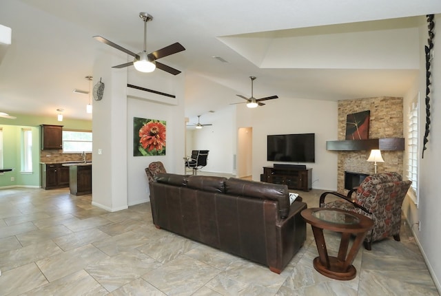 living room with ceiling fan, lofted ceiling, a fireplace, and sink