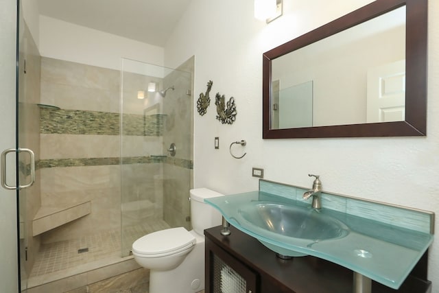 bathroom with tile patterned floors, toilet, a shower with door, and vanity