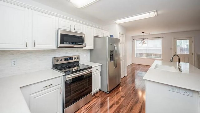 kitchen with white cabinets, dark hardwood / wood-style flooring, stainless steel appliances, sink, and hanging light fixtures