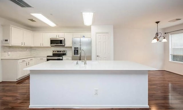 kitchen with a center island with sink, decorative backsplash, an inviting chandelier, appliances with stainless steel finishes, and white cabinets