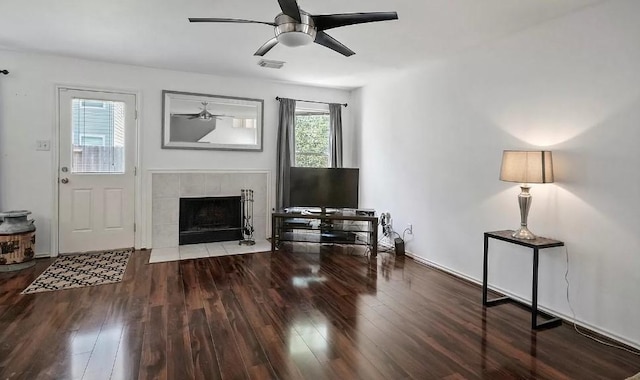 living room with hardwood / wood-style flooring, ceiling fan, and a tiled fireplace