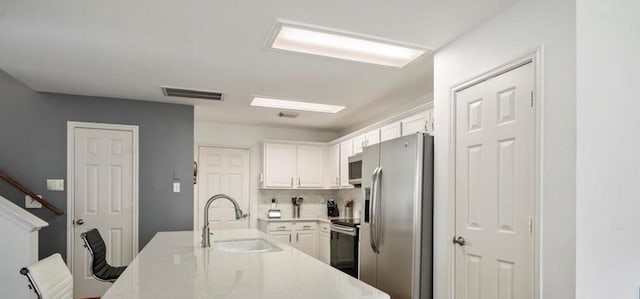 kitchen featuring white cabinets, decorative backsplash, sink, and stainless steel appliances