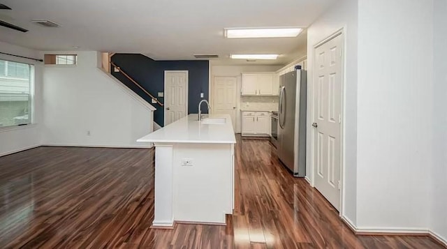 kitchen with a center island with sink, stainless steel fridge, backsplash, white cabinets, and sink