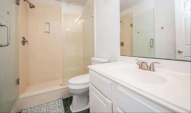 bathroom featuring a shower with door, toilet, and vanity