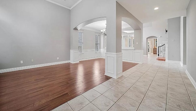 unfurnished living room featuring an inviting chandelier, ornamental molding, and light tile patterned flooring