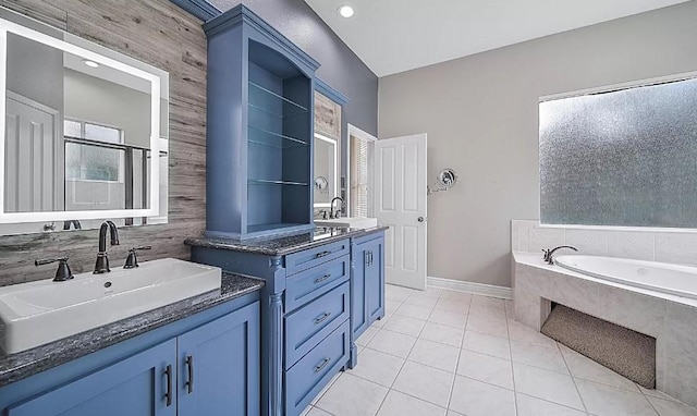 bathroom featuring a relaxing tiled tub, vanity, and tile patterned flooring