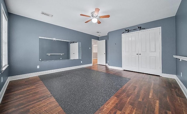 unfurnished bedroom with dark wood-type flooring, ceiling fan, and a closet